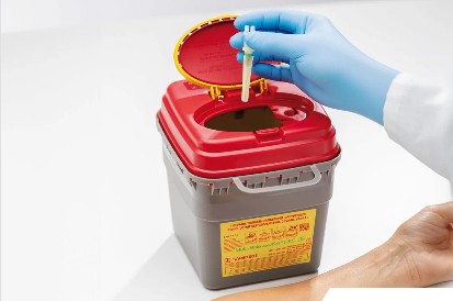 medische afval, biohazard container, rode deksel, naaldencontainer, gloved hand